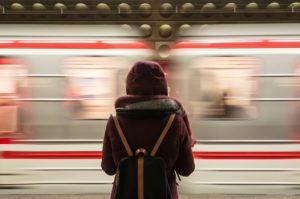 Woman standing on a train platform as the train zooms by.